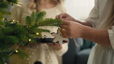 Kaukasisches-Kleines-Mädchen-Und-Mutter-Schmücken-Weihnachtsbaum-Mit-Lebkuchenanhänger.