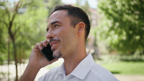 joyful boss talking mobile phone summer greenery background closeup. happy man