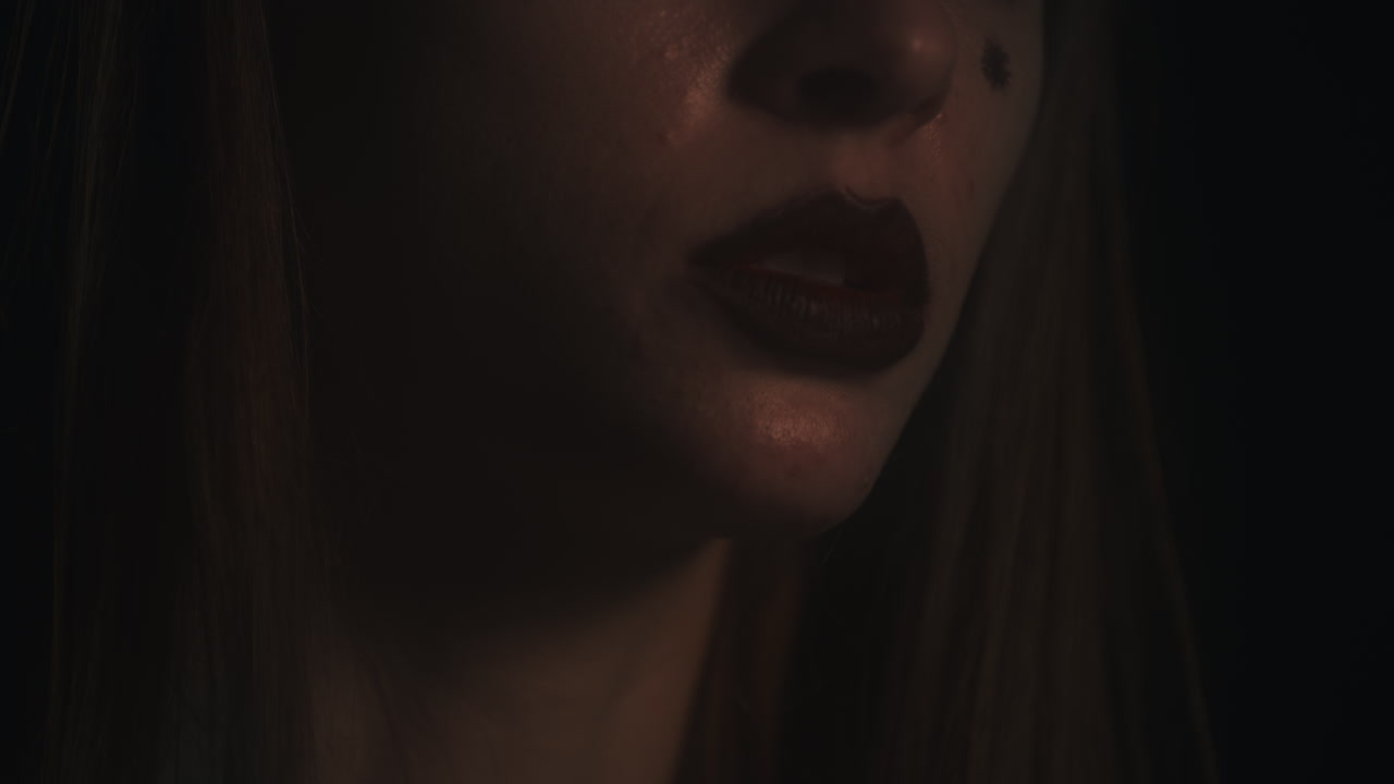 Closeup of Young Woman's Face Mouth Chanting and Meditating in the Darkness