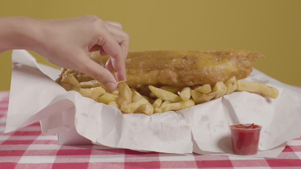 personas que usan los dedos para comer una comida tradicional británica de pescado y papas fritas con ketchup 1