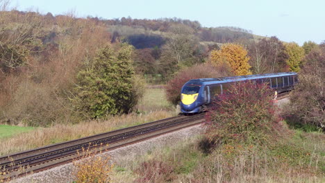 Aerial-view-of-a-small-commuter-train-passing-through-the-Kent-Countryside,-UK