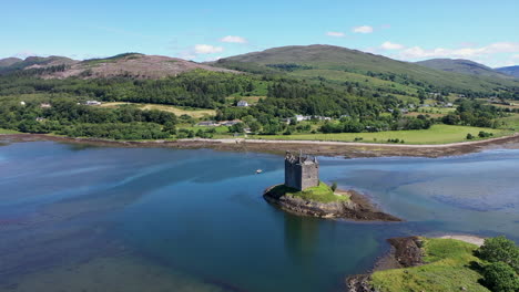 Beautiful,-slow-drone-shot-of-Castle-Stalker-from-a-distance,-slowly-panning-around-the-castle-and-showing-off-the-surrounding-scenery