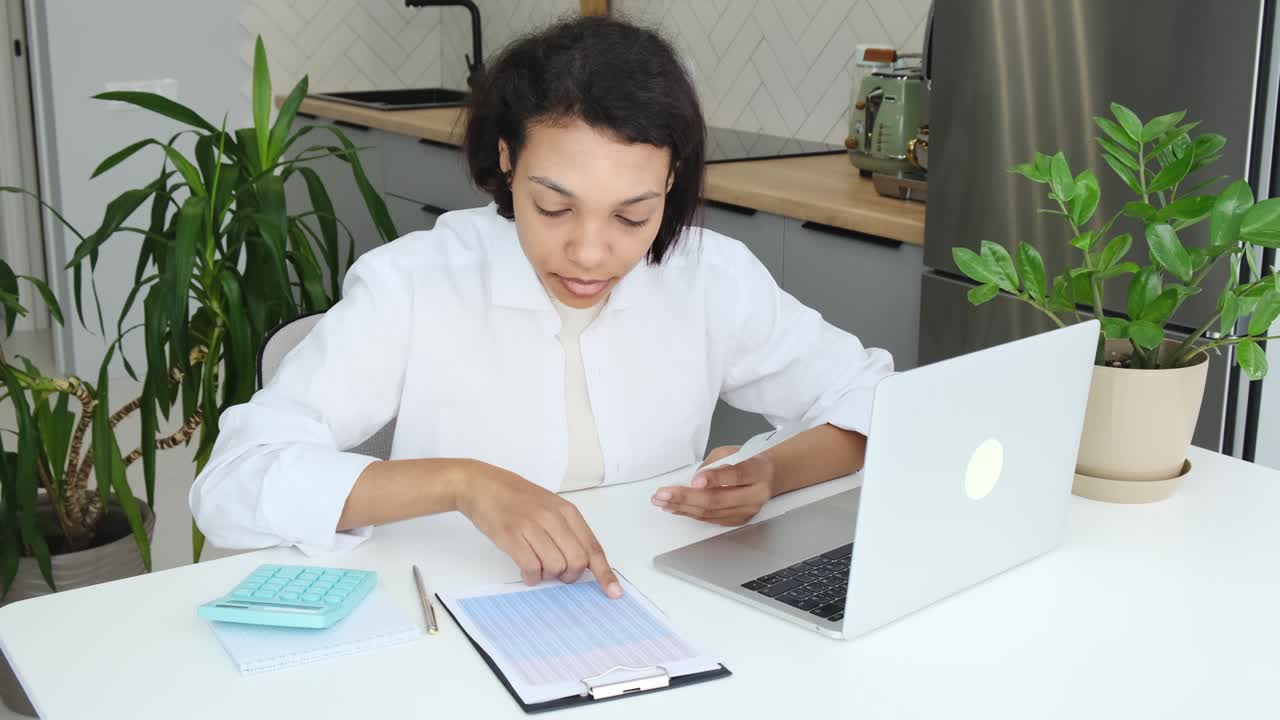una joven afroamericana seria usando una calculadora una computadora portátil administrando la planificación de las finanzas del hogar calculando el pago del alquiler facturas contando los impuestos sentarse en el sofá en