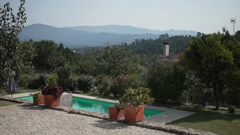 jardín sereno con una piscina y plantas en maceta, con vistas a montañas lejanas