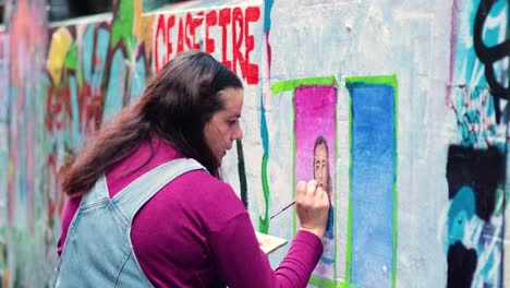 retrato de mujer pintando en una pared cubierta de graffiti