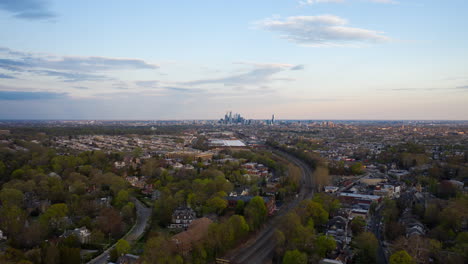 Timelapse-De-Drones-Aéreos-Del-Horizonte-De-Filadelfia-Con-Cielos-Azules-De-Los-Suburbios-Sobre-árboles-Verdes-De-Verano-Y-Vías-De-Tren-Septa