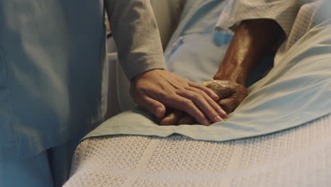 nurse touching hand of old man in hospital bed showing affection for elderly patient recovering from illness
