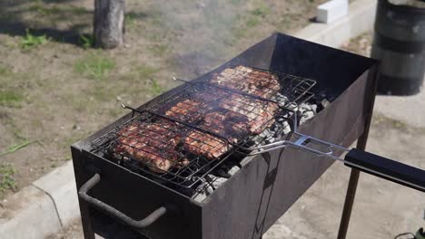 Meat-grilled-on-the-grid.-Food-for-barbecue-party.-Male-hand-is-splashing-water-to-eliminate-fire-and-turning-the-grid-around