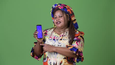 overweight beautiful african woman wearing traditional clothing against green background