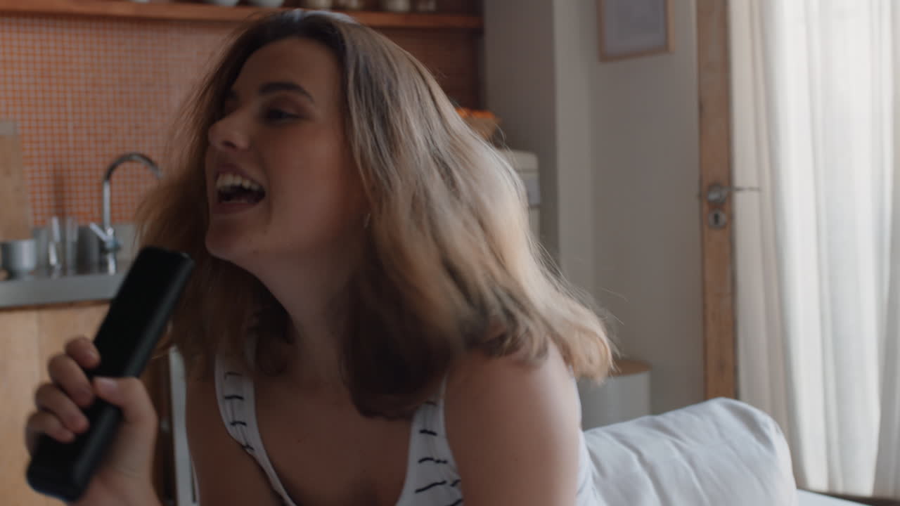 행복한 젊은 여성이 집에서 노래하고 즐겁게 성공적인 라이프 스타일을 축하하고 춤을 추고 주말에 카라오케 음악 엔터테인먼트를 즐기고