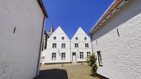static shot of the pure white building hofstraat in thorn, limburg with a view of the dutch architecture as cyclists pass by on a sunny day