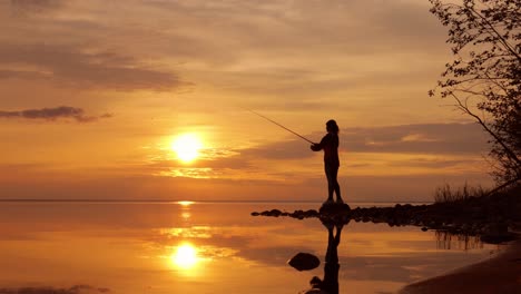 woman fishing on fishing rod spinning at sunset background.