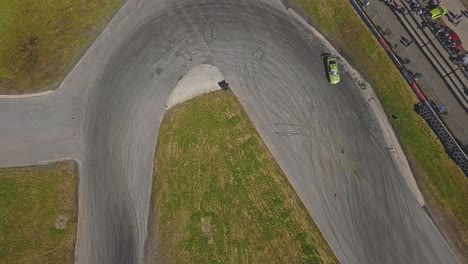 aerial shot of a car drifring on high speed on a turn, green grass and a race track, top view shot, next to viewers