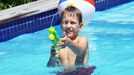 familia feliz haciendo una batalla de pistolas de agua en la piscina