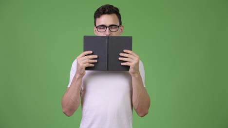 young handsome nerd man covering face with book