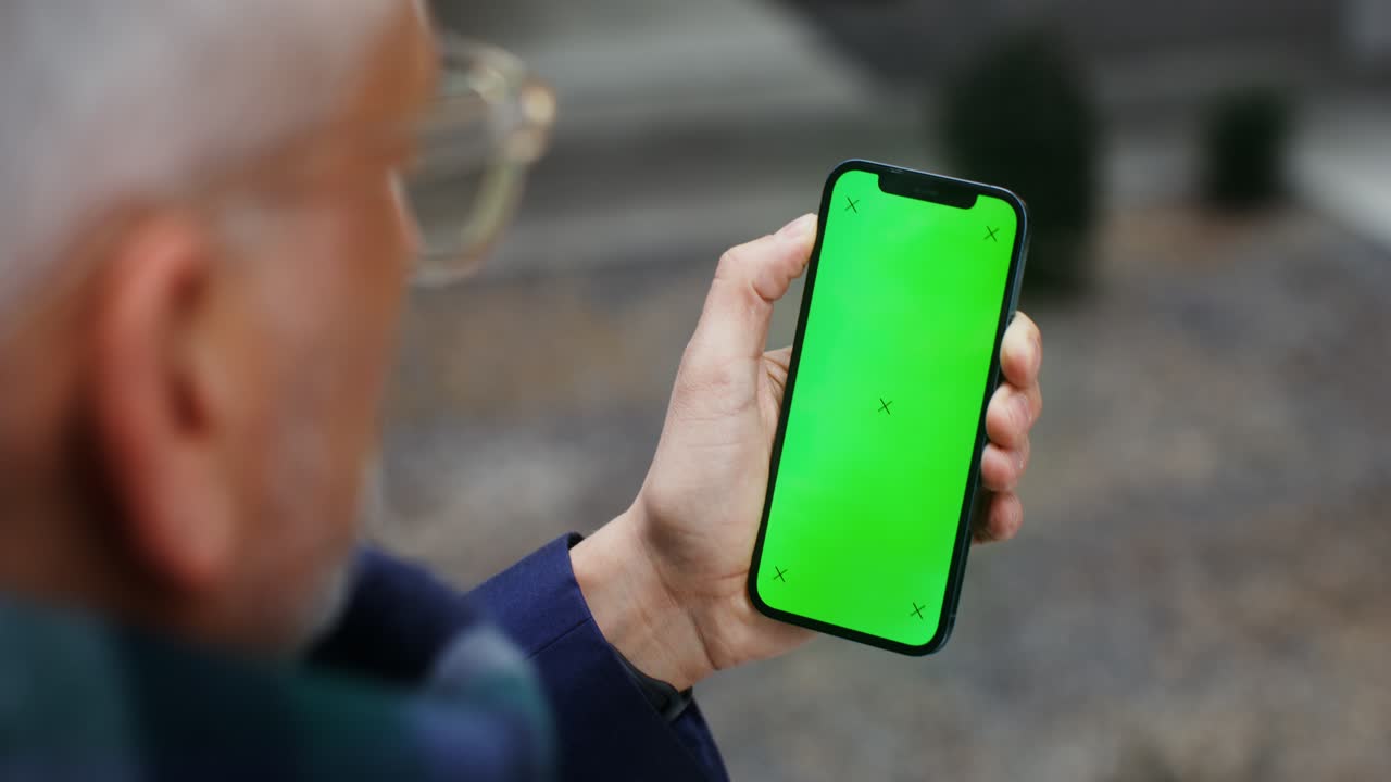adulto mayor usando un teléfono inteligente con una pantalla verde