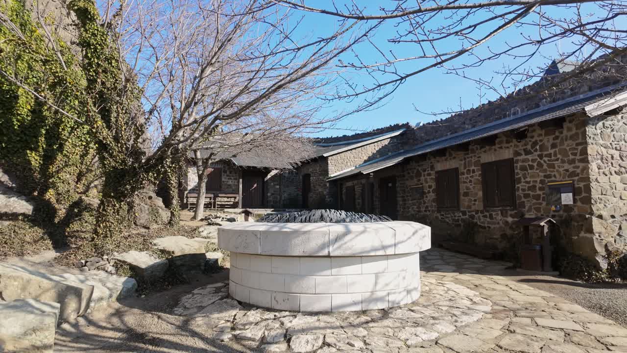 The inner garden of Hollókő Castle, Hungary, featuring a historic stone well surrounded by medieval architecture and natural elements. UNESCO World Heritage site.