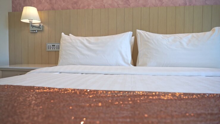 Carrellata su un letto da resort ricoperto da un piumone in rame paillettato.