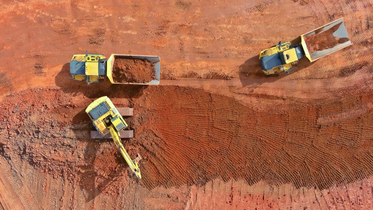 Excavator scoop loads a soil in dump truck on preparing place to construction site for residential complex house