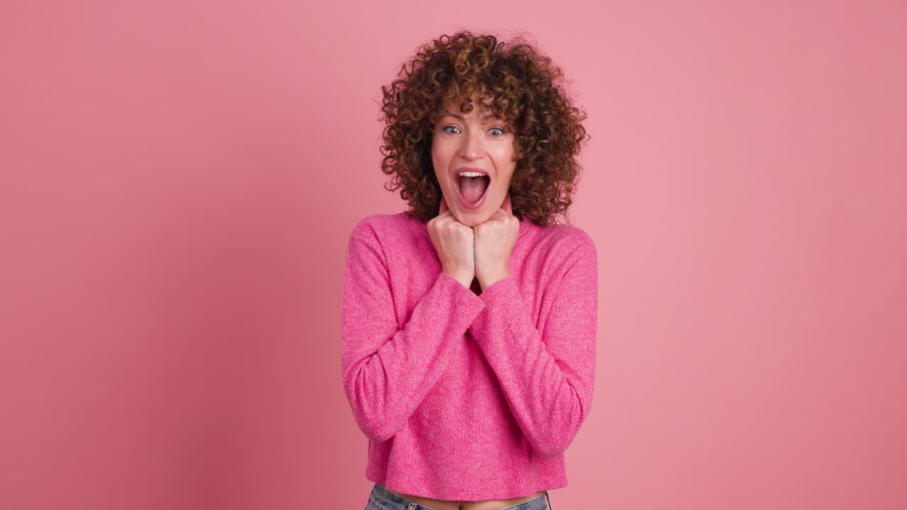 Stunned young woman standing with opened mouth on pink background