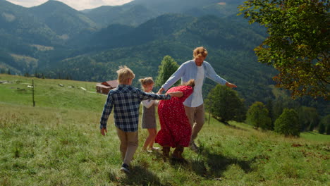 family holding hands playing active game on meadow. parents have fun with kids.