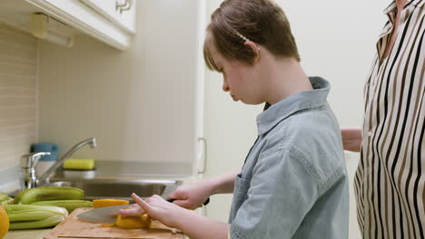 teenager cutting orange with the supervision of her mother