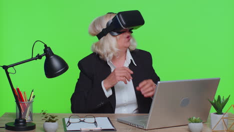 Senior-businesswoman-using-headset-helmet-app-to-play-simulation-game-watching-virtual-reality-video