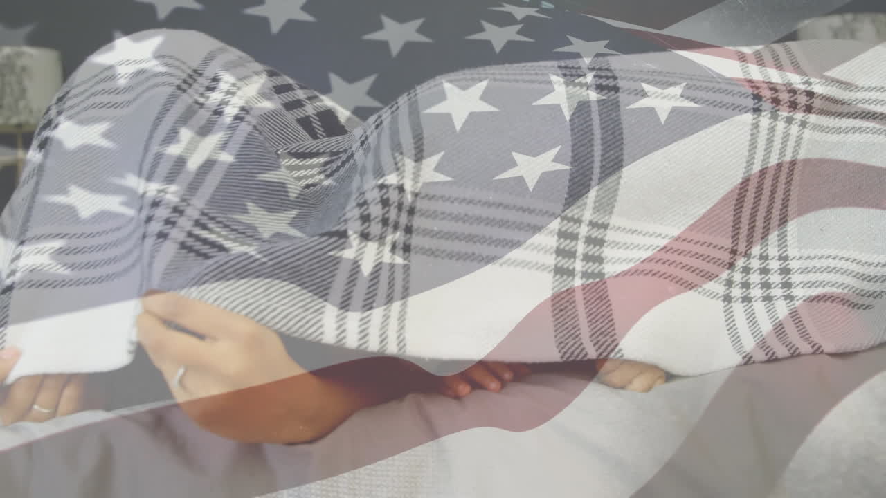 familia biracial escondiéndose bajo una manta con nuestra bandera en primer plano