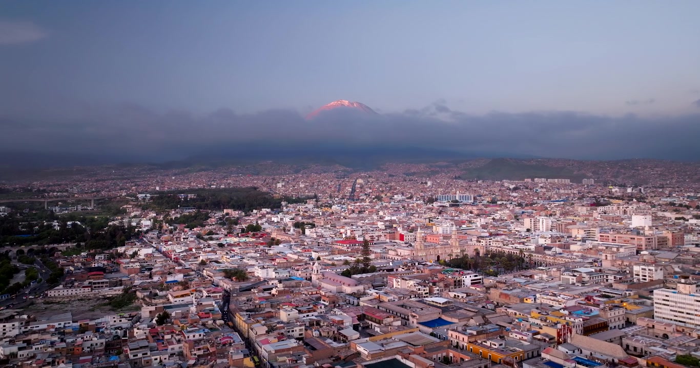 Paisaje urbano de Arequipa, la ciudad blanca, con el icónico pico del volcán El Misti visible al atardecer en Perú. Vista panorámica aérea con dron, espacio para texto