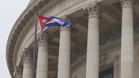 Cuban-flag-waving-in-wind-at-building-in-Havana,-Cuba