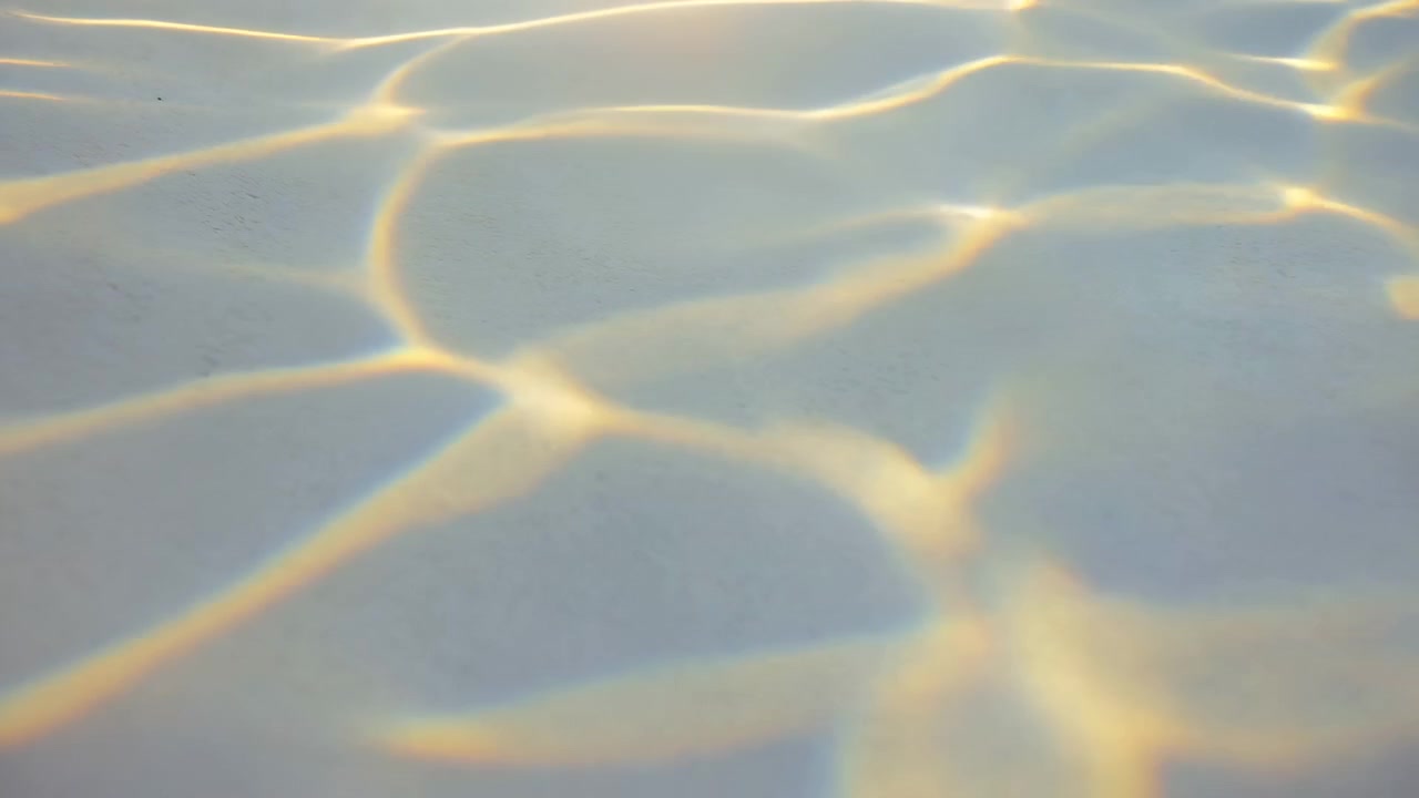 Glowing lines of reflected light drift and change across smooth translucent surface, forming calm wave-like patterns with pale tones and gentle movement in close-up vertical composition.