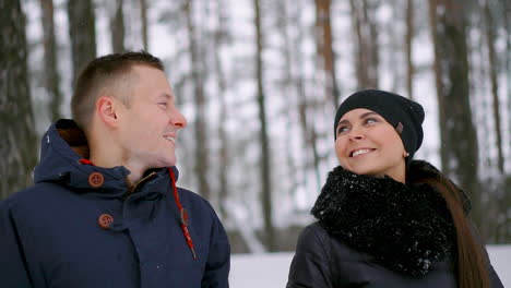 close-up of a man and a woman in love standing in the winter forest hugging each other and looking into the distance