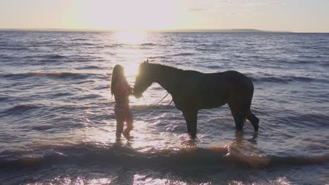 mujer y caballo bañándose en el lago al atardecer