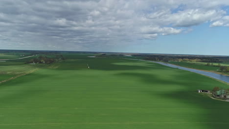 aerial - flight over lush green meadow on bright cloudy day