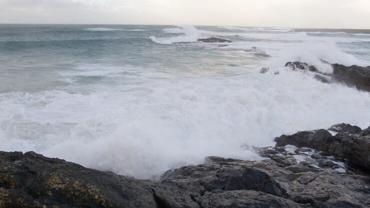 Ripresa al rallentatore di grandi onde che si infrangono sulla scogliera durante una tempesta nella baia vicino alla spiaggia di Tangasdale, vicino a Castlebay sull'isola di Barra.