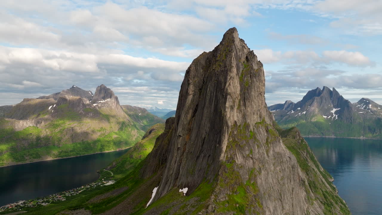 Il monte Segla a Senja, in Norvegia, sotto il sole di mezzanotte, che rivela ripide scogliere, pendii verdi e le acque profonde del fiordo in una luce estiva cinematografica, vista aerea