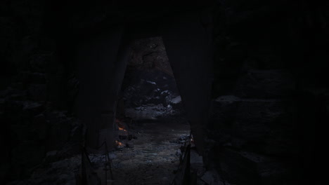 entrada a una cueva oscura que conduce a un interior rocoso con luz parpadeante