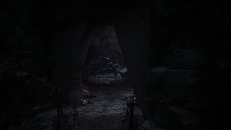 dark cave entrance leading to a rocky interior with flickering light