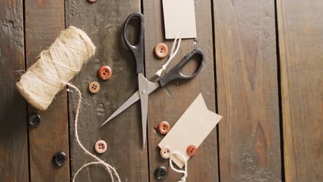 video of scissors, twine string, buttons and gift tags on dark wood boards with copy space