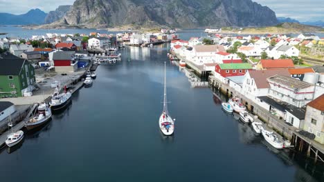 boat sails in henningsvaer harbour, lofoten island, norway, scandinavia - 4k aerial reveal