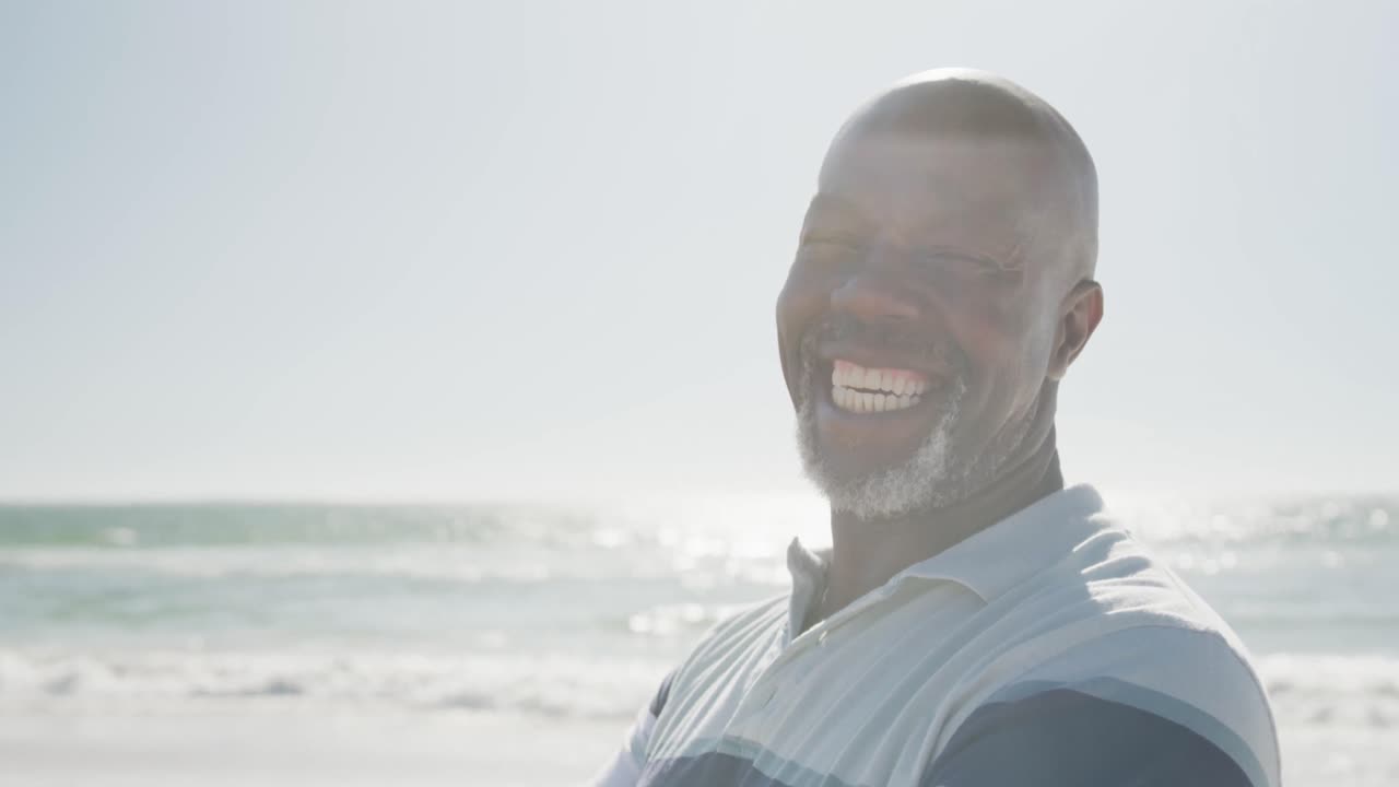 Portrait of happy senior african american man smiling at beach, in slow motion, with copy space