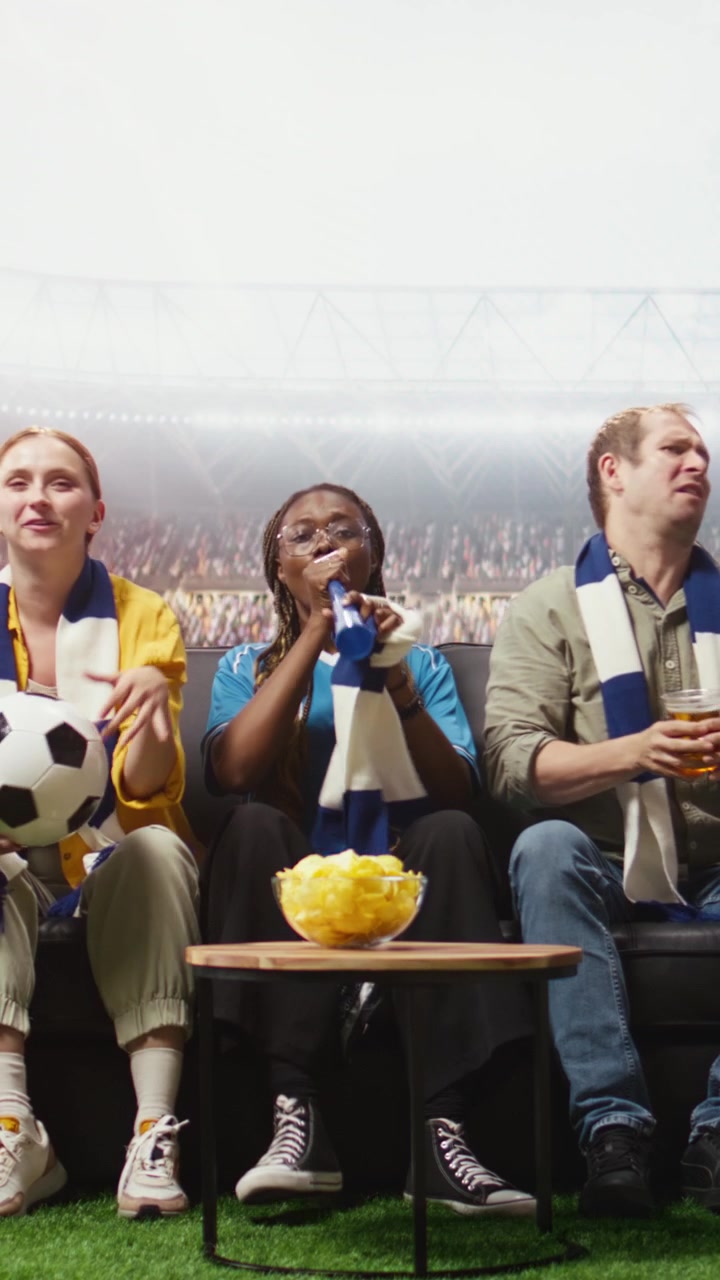 Video vertical. Aficionados de fútbol ven el partido en casa en una transmisión inmersiva, ambiente de estadio