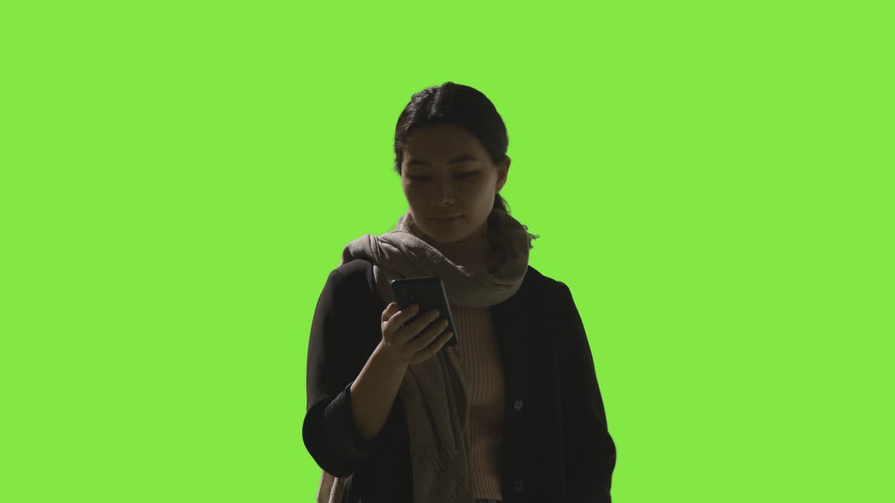 Low Key Studio Shot Of Woman Using Mobile Phone Against Green Screen 1