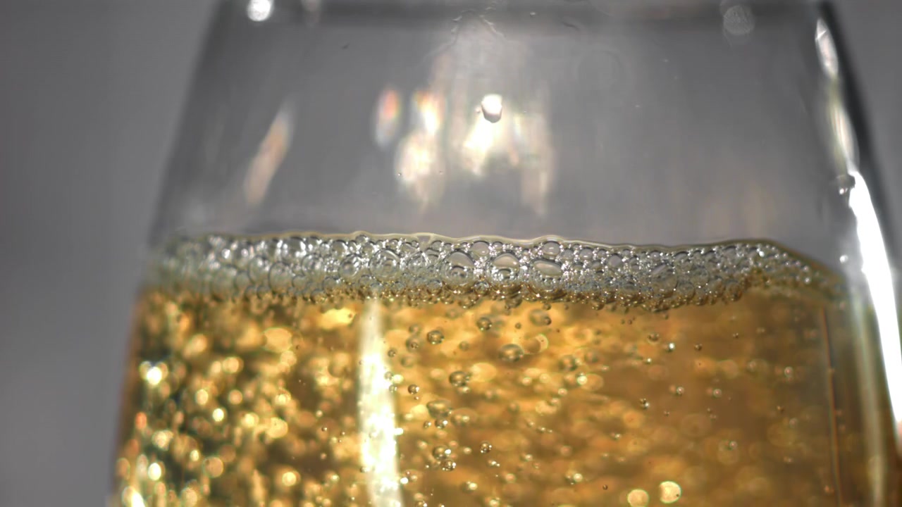 Primo piano di bollicine dorate di champagne che salgono in un bicchiere