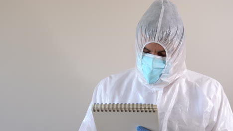 doctor en traje ppe escribiendo en un cuaderno