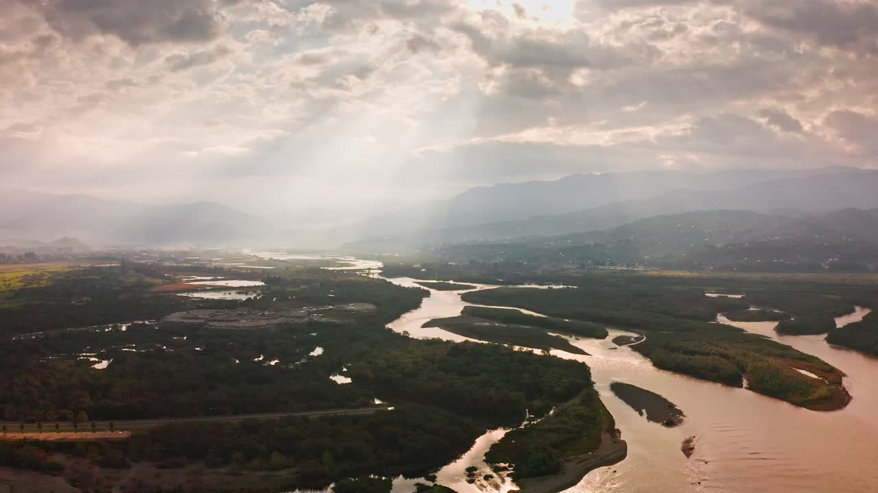 구불구불한 강어귀와 조지아의 산악 아자라 지역 근처 삼림 계곡의 풍경 위의 극적인 클라우드스케이프를 통해 빛나는 태양
