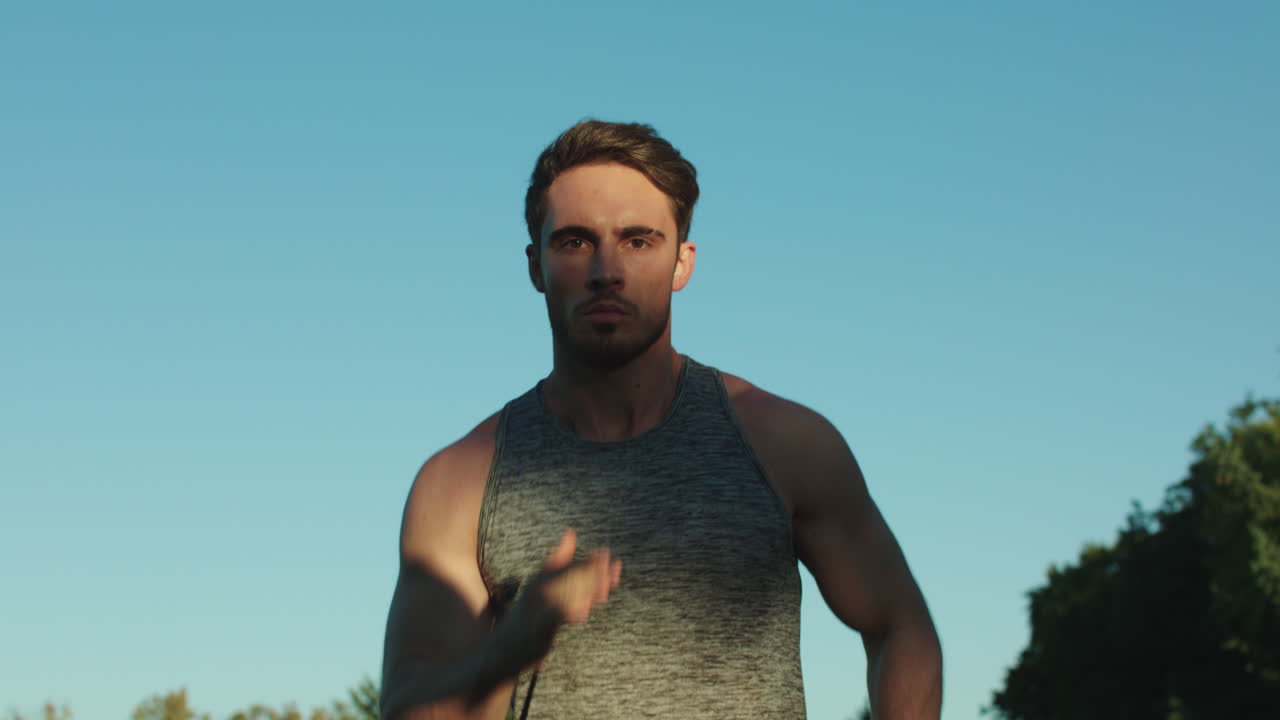corredor masculino entrenando ejercicio cardiovascular en el parque. hombre deportivo corriendo en el cielo azul