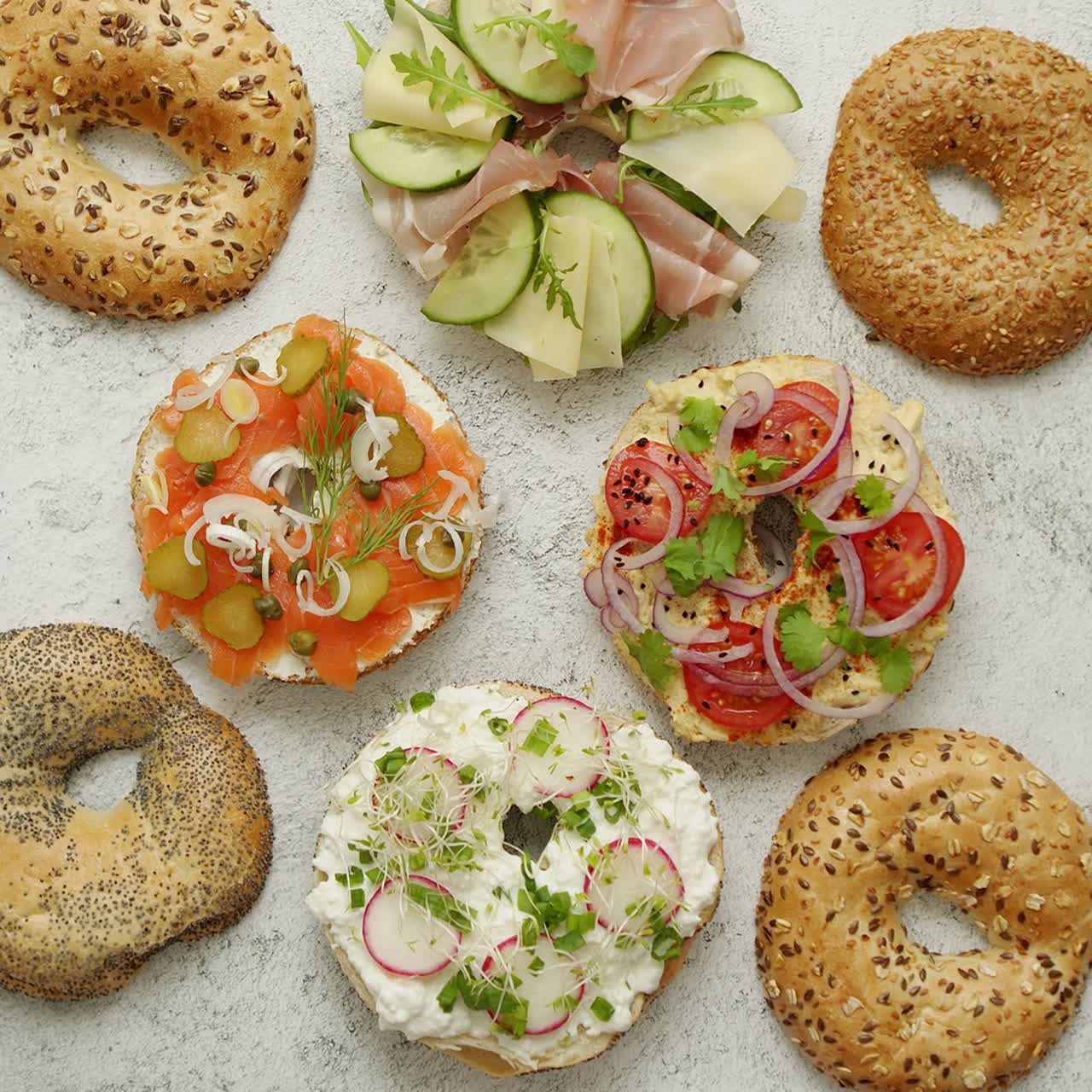 Bagel farciti con vari condimenti: salmone, ricotta, hummus, prosciutto, ravanelli ed erbe fresche
