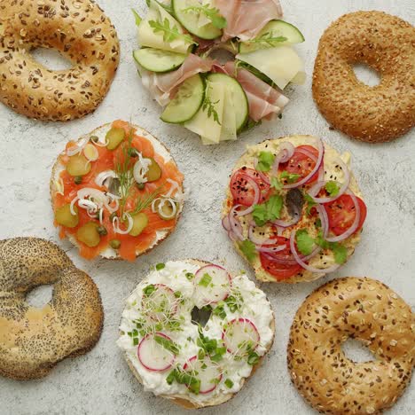 Bagel-sandwiches-with-various-toppings--salmon--cottage-cheese--hummus--ham--radish-and-fresh-herbs