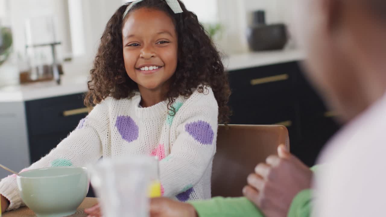 Video di una felice figlia afroamericana che ride con i genitori al tavolo da pranzo